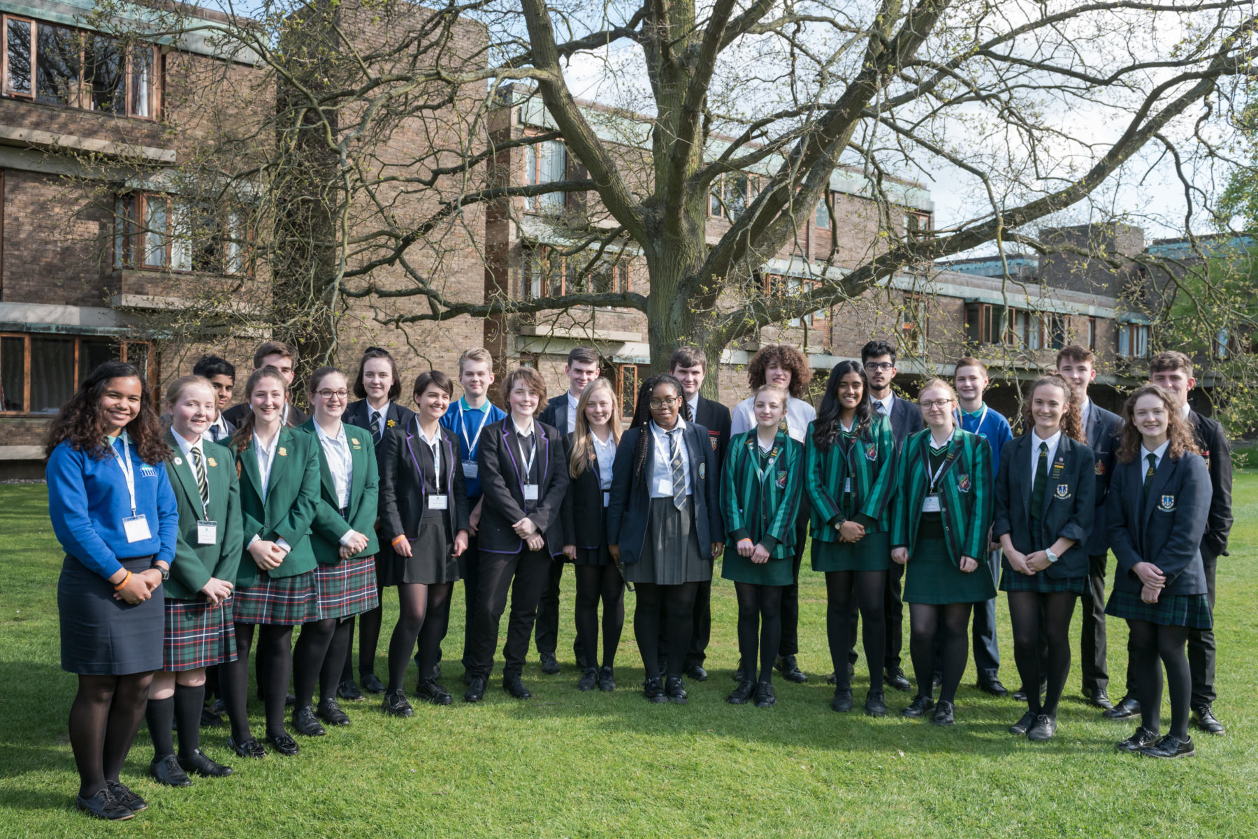 A group of students from different schools posing for a picture in the garden