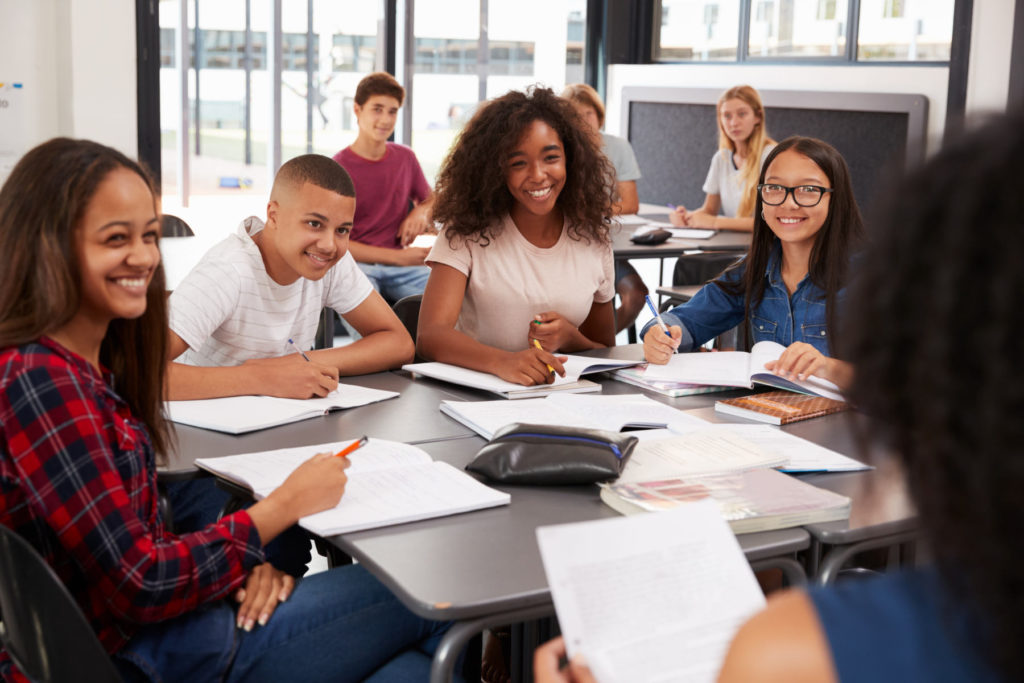 Group of secondary school students sitting in the classroom and looking at the teacher