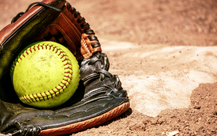 An image of softball inside the catcher's glove on the ground