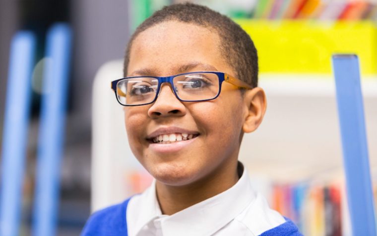 A close-up picture of a young boy wearing lens glasses.