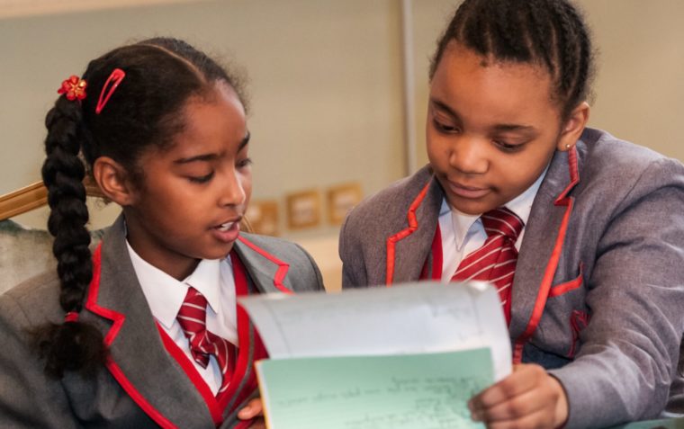 Image of two primary kids reading their debate notes
