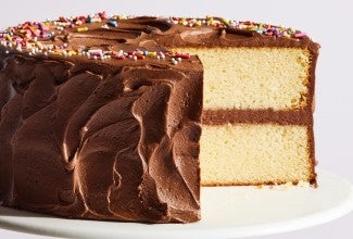 Chocolate frosted birthday cake with a slice cut out of it