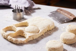 Biscuit dough being stamped out with biscuit cutter