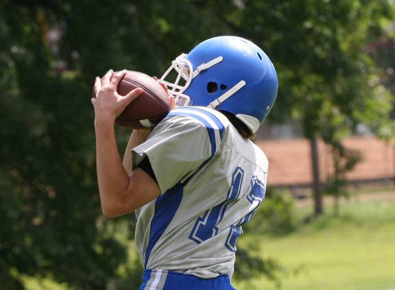 Child in American Football uniform holding ball.
