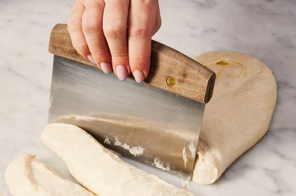 Bench knife being used to cut up wet bread dough