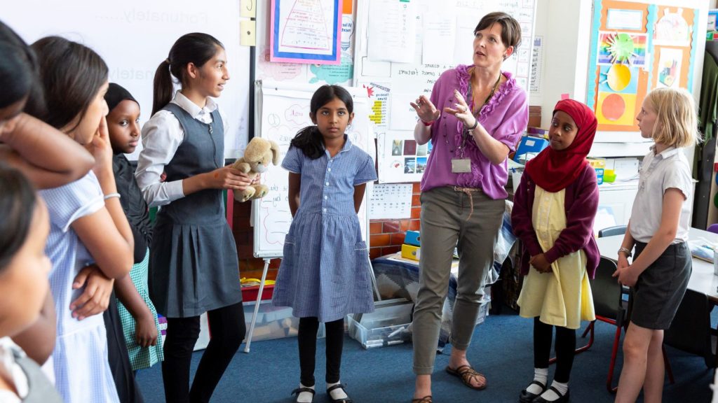 Liezel Closer is speaking to primary school pupils inside a classroom and listening to the tutor speaks.
