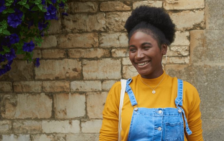 Fatima pictured with a bright yellow top infront of astone wall