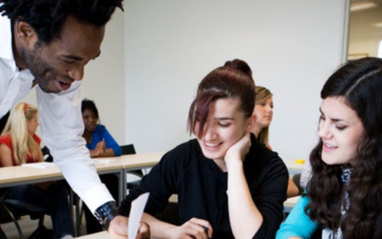 A photo of a person writing down his ideas while two other people joyfully watch him