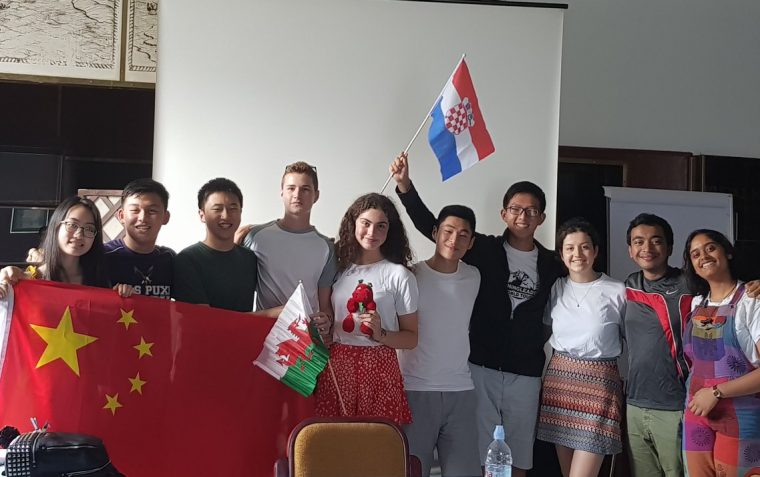 A picture of students at the World Schools Debate Championship waving the national flags of China, Wales, and Croatia