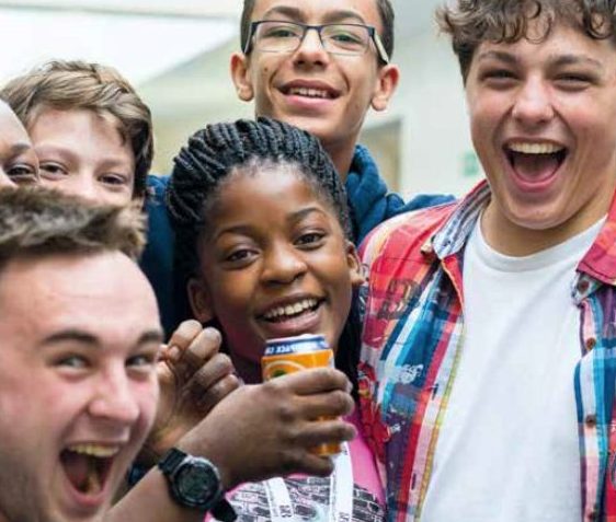 A group of pupils smiling for a photo with one of them holding a fanta can